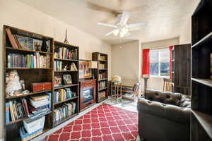 Living area with a textured ceiling, a ceiling fan, and light carpet