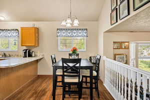 Dining space with dark wood finished floors, a chandelier, and lofted ceiling