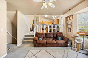 Living area with a ceiling fan and light colored carpet