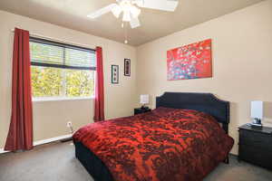Carpeted bedroom with a ceiling fan and a textured ceiling