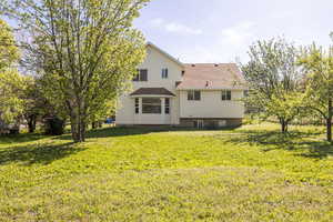 Back of house featuring a yard and roof with shingles
