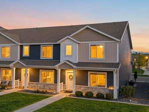 Craftsman house with a lawn, covered porch, stone siding, and a shingled roof