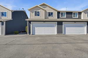 View of front of house with board and batten siding, an attached garage, and asphalt driveway
