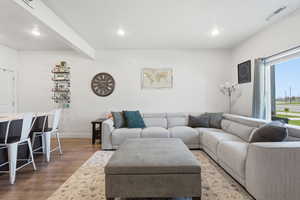 Living room with light wood-style flooring and recessed lighting