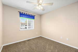 Spare room featuring dark colored carpet and ceiling fan