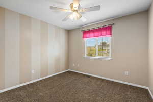 Unfurnished room featuring a ceiling fan and dark carpet