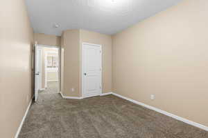 Unfurnished bedroom with dark carpet, a textured ceiling, and a closet