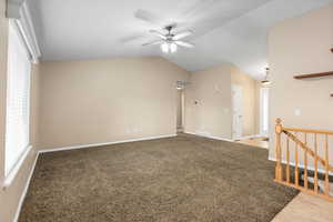 Unfurnished room featuring ceiling fan, light carpet, and lofted ceiling