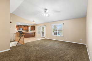 Unfurnished living room with light colored carpet, suspended lighting, ceiling fan, and lofted ceiling