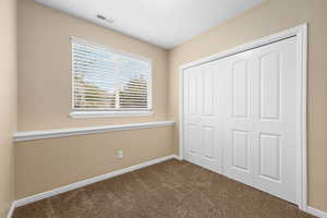 Unfurnished bedroom featuring dark carpet and a closet