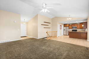 Kitchen with open floor plan, light colored carpet, stainless steel appliances, wood finish cabinets, and ceiling fan