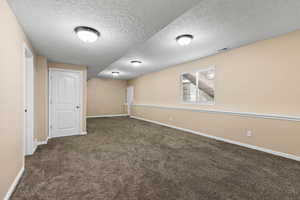 Spare room featuring a textured ceiling and dark carpet
