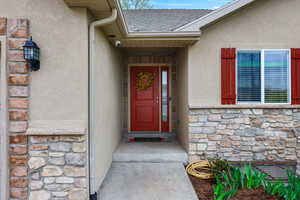 Property entrance featuring stone siding, stucco siding, and a shingled roof