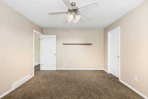 Unfurnished room featuring dark carpet and ceiling fan