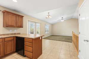 Kitchen featuring a peninsula, wood finish cabinetry, ceiling fan, black dishwasher, and suspended lighting