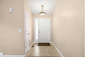 Foyer entrance with light tile patterned floors and baseboards