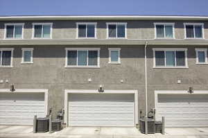Rear view of house featuring an attached garage and stucco siding