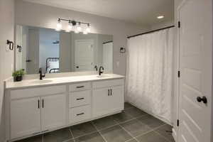 Bathroom with double vanity, dark tile patterned floors, ensuite bath, and recessed lighting
