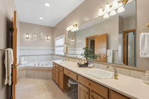 Full bath featuring a garden tub, double vanity, a wainscoted wall, light tile patterned floors, and recessed lighting