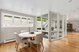 Dining room featuring a baseboard heating unit, light wood finished floors, and a chandelier