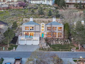 Front view of property with a chimney, a garage, concrete driveway, and a balcony