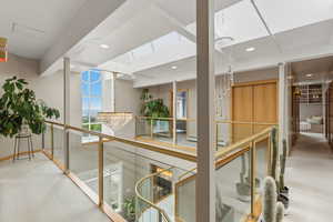 Corridor with light colored carpet, a chandelier, and an upstairs landing