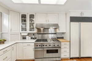 Kitchen featuring premium appliances, light countertops, glass fronted cabinets, and white cabinets