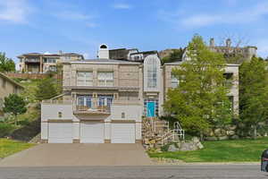 View of front facade featuring an attached garage, stucco siding, concrete driveway, a balcony, and a front yard
