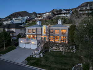 View of front of property featuring a mountain view, a chimney, stone siding, a front yard, and an attached garage