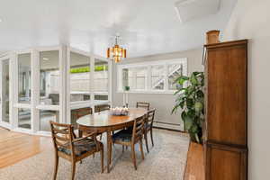 Dining room with hanging lights, light wood-type flooring, and a baseboard radiator