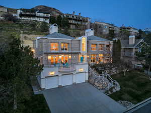 View of front of property with an attached garage, driveway, a front lawn, and a patio