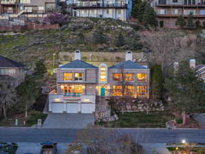 Rear view of house featuring a chimney, an attached garage, a balcony, and concrete driveway