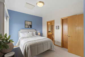 Bedroom featuring light carpet and ensuite bath