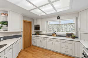 Kitchen featuring open shelves, white cabinetry, light wood-type flooring, and stainless steel appliances