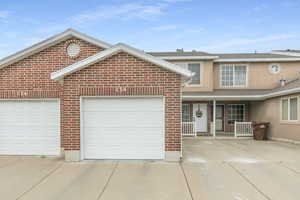 Traditional home featuring concrete driveway, covered porch, an attached garage, and brick siding