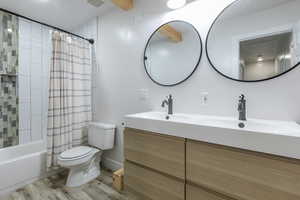 Full bath featuring double vanity, shower / tub combo with curtain, and light wood-style flooring