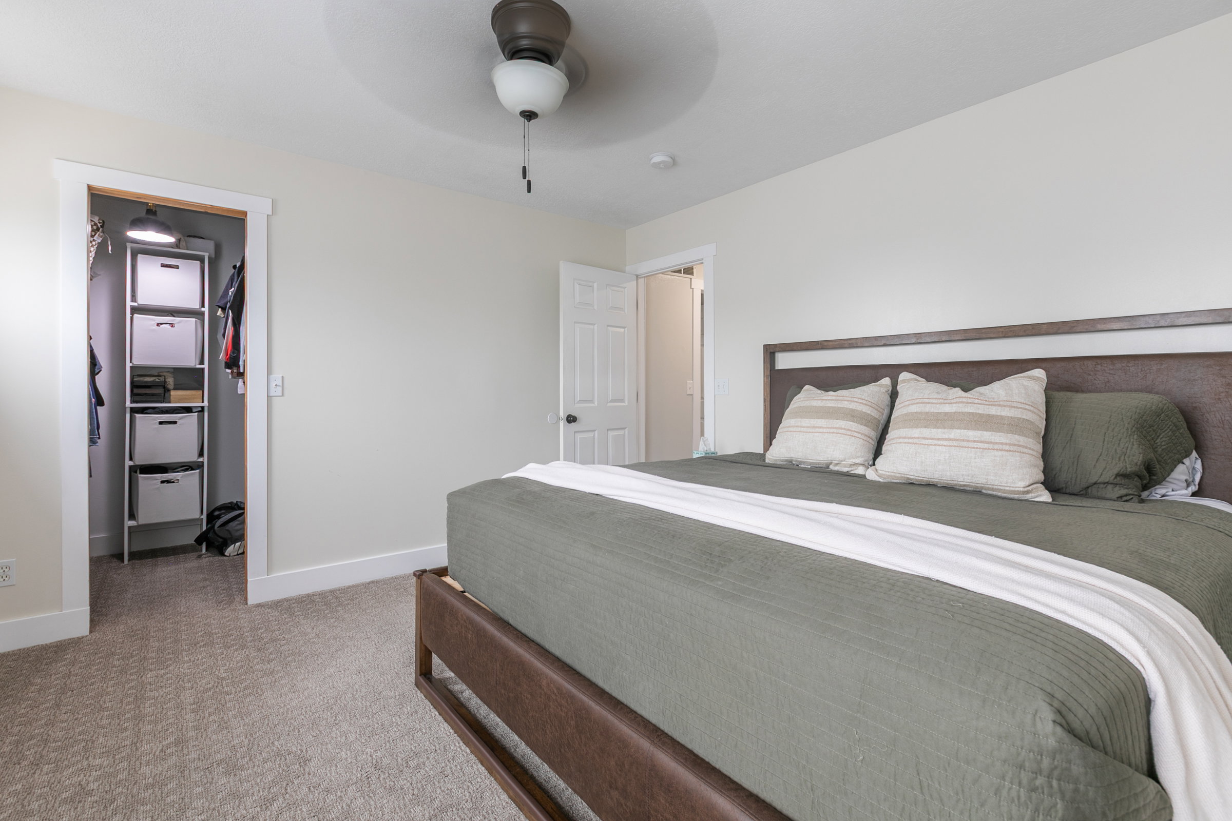 Carpeted bedroom featuring a spacious closet and ceiling fan