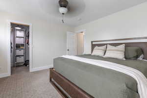 Carpeted bedroom featuring a spacious closet and ceiling fan