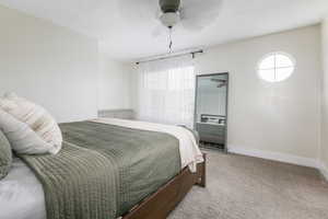 Carpeted bedroom with multiple windows and ceiling fan