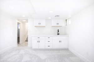 Bar with white cabinetry, light colored carpet, and light countertops