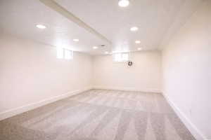 Basement with light carpet, plenty of natural light, a textured ceiling, and recessed lighting