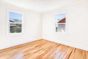 Unfurnished room featuring light wood-type flooring, healthy amount of natural light, and ornamental molding
