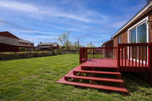 View of grassy yard featuring a deck