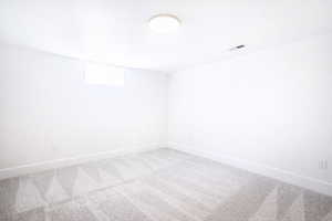 Empty room featuring light colored carpet and baseboards