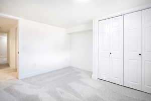 Unfurnished bedroom with light carpet, a textured ceiling, and a closet