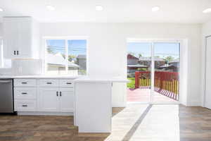 Kitchen featuring white cabinets, stainless steel dishwasher, dark wood finished floors, recessed lighting, and a peninsula