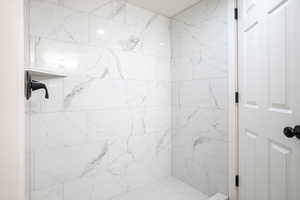Full bathroom with a marble finish shower