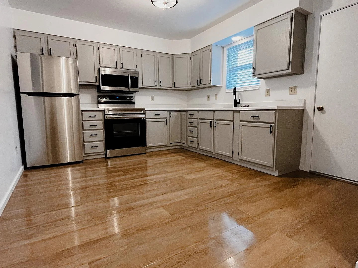 Kitchen featuring gray cabinets, stainless steel appliances, light countertops, and light wood-type flooring