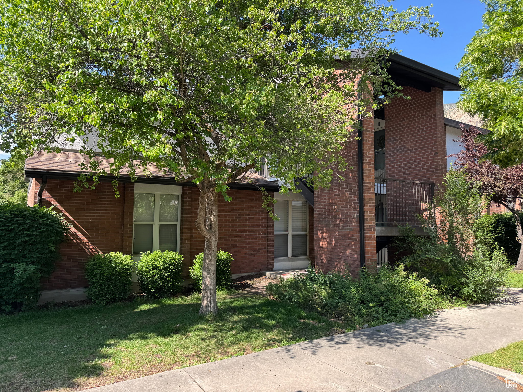 View of front of home featuring a balcony, a front lawn, and brick siding