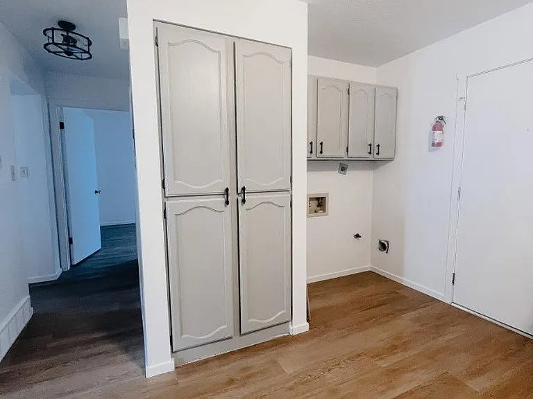 Laundry room featuring dark wood-style floors, cabinet space, and hookup for a washing machine